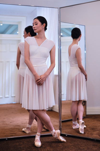 Dancer standing in a Dawn White Pull-On Full-Circle Ballet Rehearsal Skirt and matching leotard, the sheer mesh beautifully drapes to mid-calf 