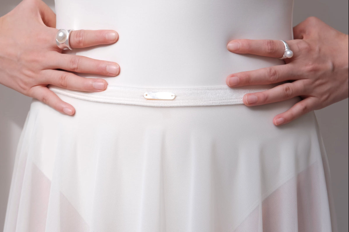 Close-up details of Pull-On Full-Circle Ballet Rehearsal Skirt in dawn white, showing the stretch velvet waistband and the hand-sewn mother-of-pearl tag